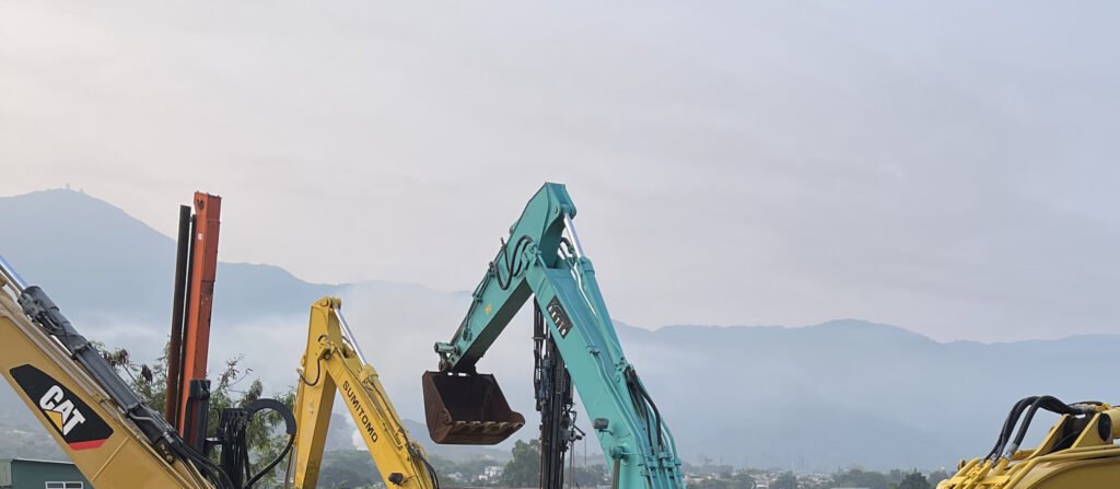 Real equipment structures in a wider outdoor mechanical setting, with a mountain backdrop and sky.