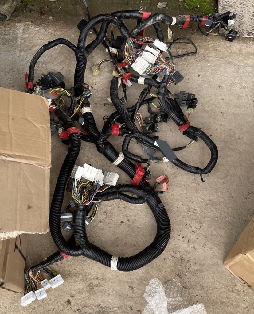 Several curved sleeved wiring runs and connector groups arranged on the ground, with overlapping sections visible.