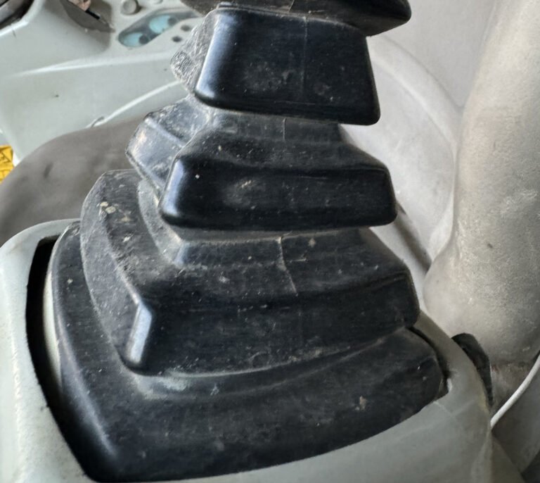 Close detail of broad black bellows folds meeting a pale grey console opening beside a seat.