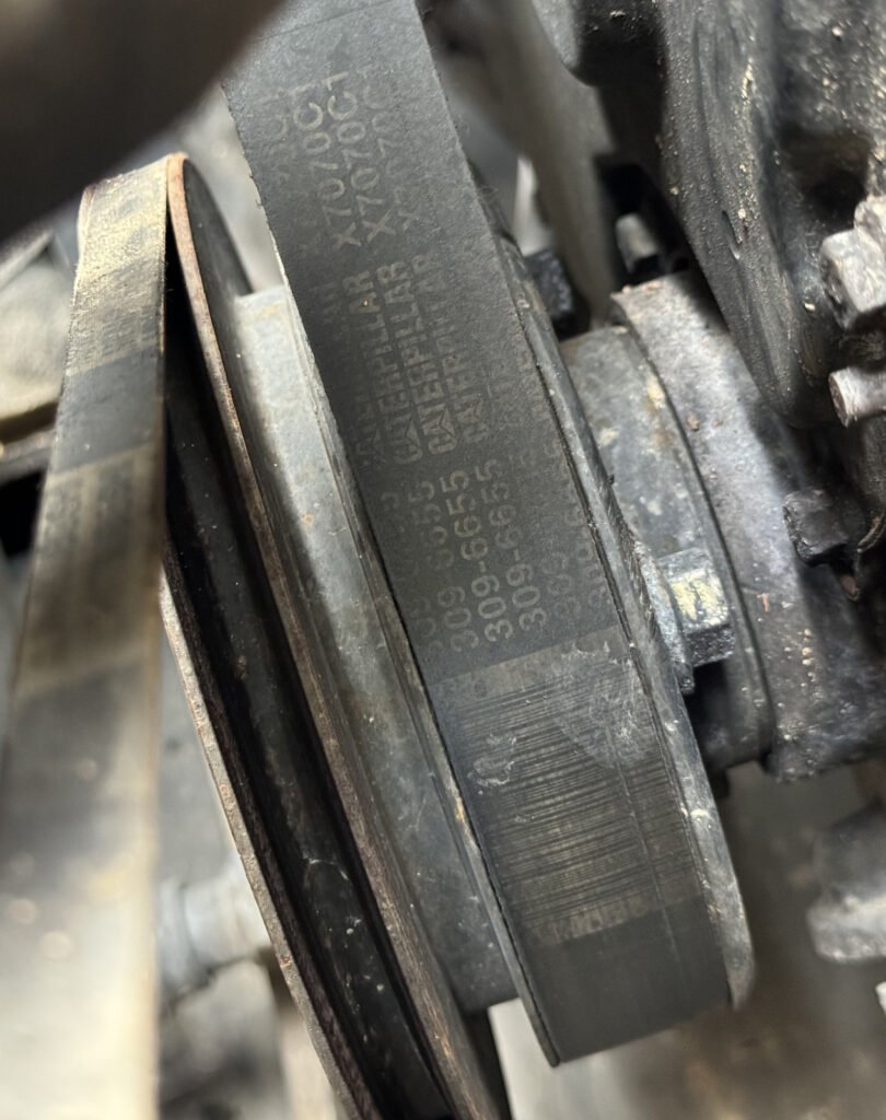 Close-up of a black belt face beside a recessed metal pulley groove and a partly visible hub.