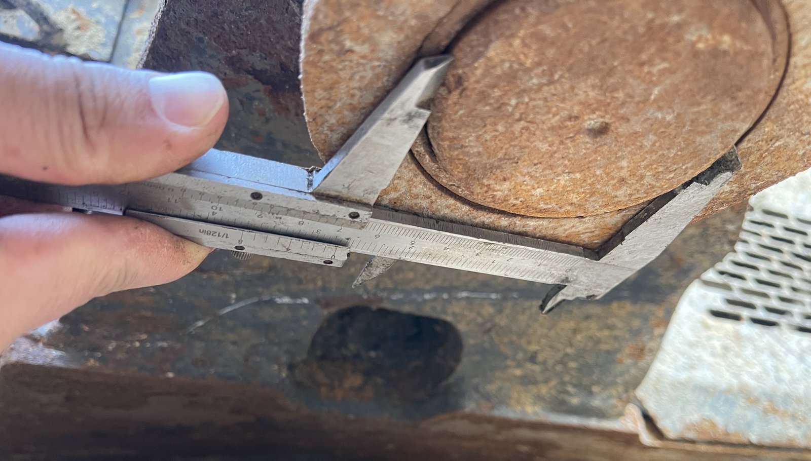 A caliper positioned across a rust-coloured circular metal feature.