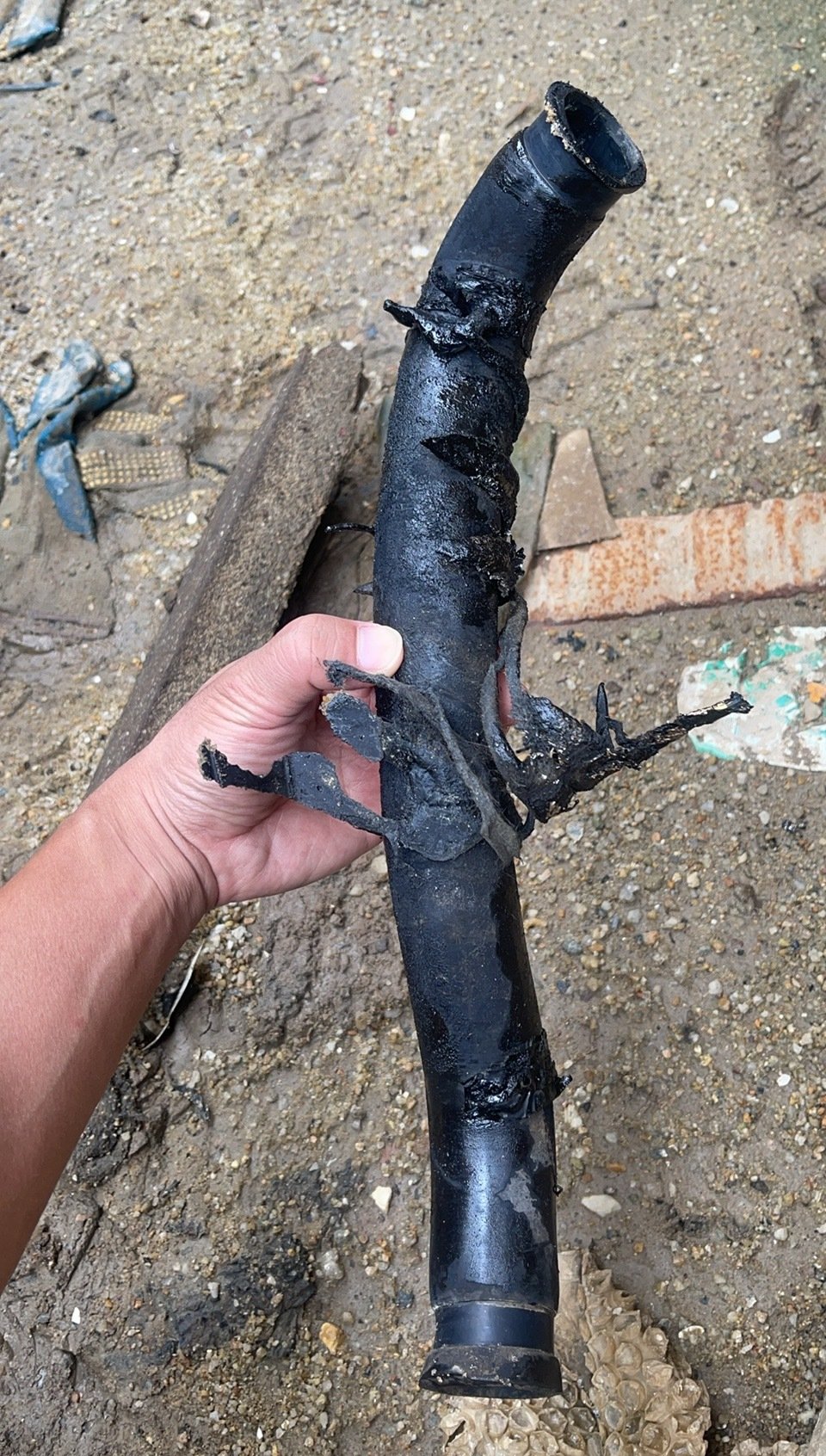 A hand-held dark hose with visibly loose surface layers and both end regions in view.