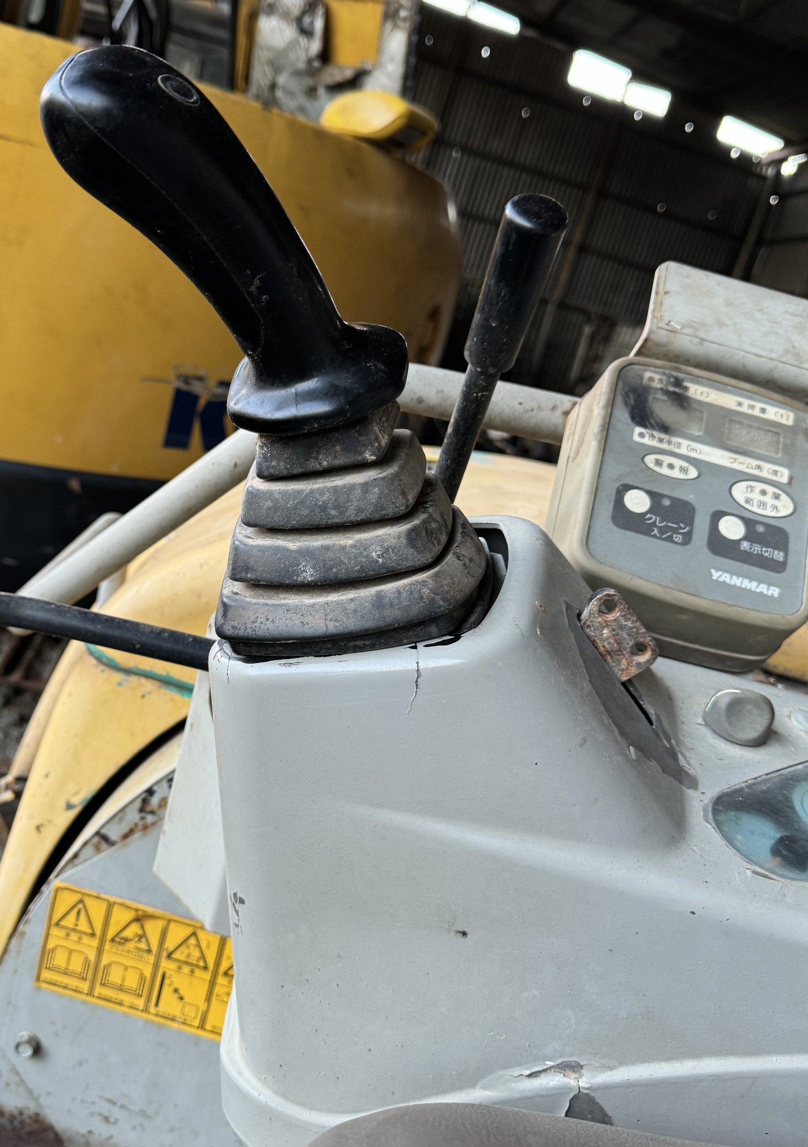 A cab control lever, bellows, base and nearby operator panel.