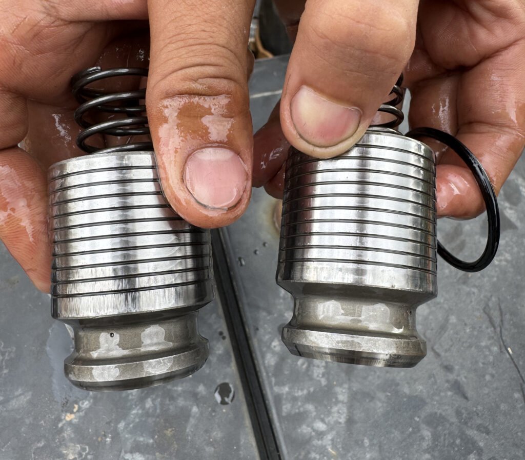Hands hold two grooved metal bodies with broad upper sections, narrower lower regions and wider lower lips; a dark ring is visible beside one.