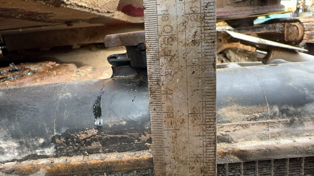 A close profile of a dark radiator tank and a raised feature beside a ruler, with part of the finned section below.