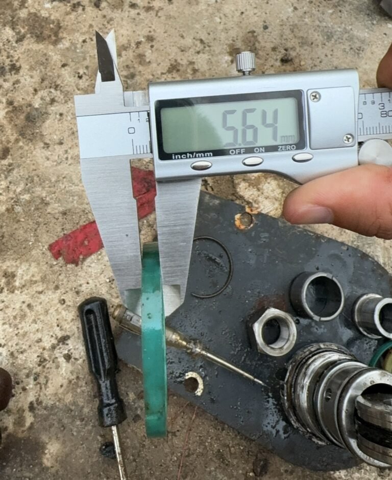 Green curved band held across a local dimension between caliper jaws, with separate metal pieces nearby.